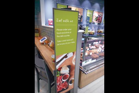 At the back of the store next to the deli counter is a further grazing station with a graphic that requests shoppers to “Please order your food and drink at the deli counter. Take a seat and we’ll serve you at your table.”